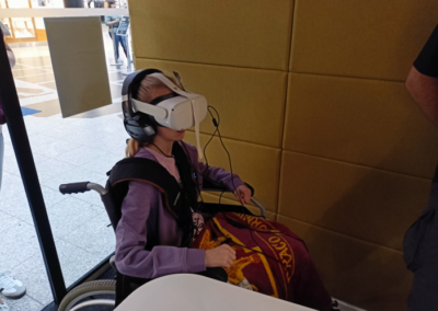 Dziewczyna na wózku inwalidzkim w okularach VR i kamizelce haptycznej.