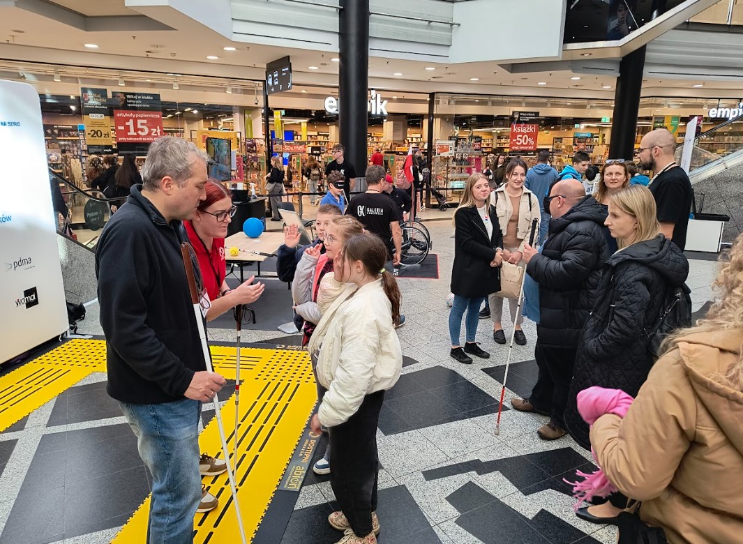 Dzieci słuchają niewidomego trenera, który opowiada im o swojej białej lasce.